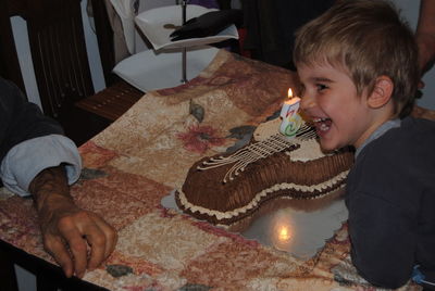 Cheerful boy with birthday cake looking away at home