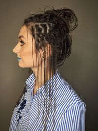 Profile view of thoughtful young woman with hairstyle against brown background