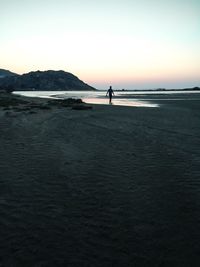 Silhouette man standing on beach against clear sky