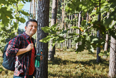 Man with backpack hiking in forest, actively spending summer vacation close to nature