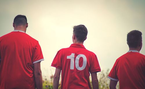 Rear view of men standing against sky