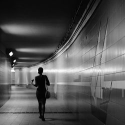 Rear view of woman walking in illuminated corridor