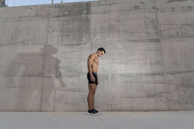 Full length of a young man standing against wall