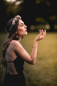 Side view of woman blowing dandelion seed