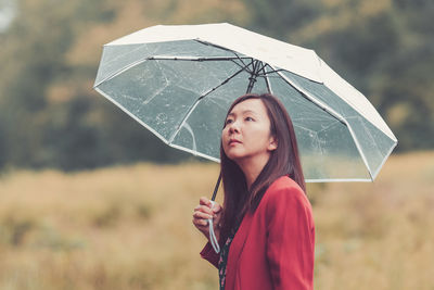 Portrait of woman with umbrella standing during rainy season