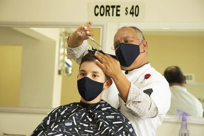 View of barber cutting hair of boy at barber shop