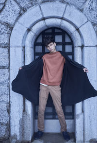 Portrait of young man standing against door