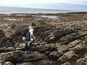 Full length of woman walking on rocks at beach