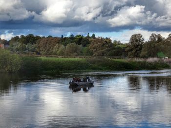People in boat on river against sky