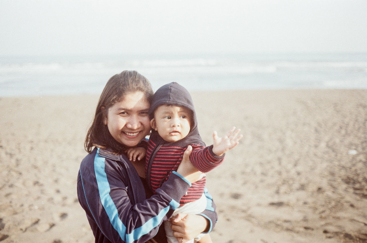 land, beach, sea, water, togetherness, childhood, happiness, emotion, sky, smiling, nature, two people, horizon over water, sand, horizon, portrait, child, women, looking at camera, positive emotion