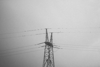 Low angle view of electricity pylon against clear sky