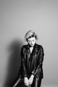 Portrait of young woman standing against wall