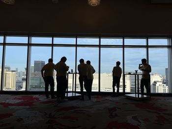 Rear view of people standing in glass window