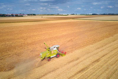 Aerial view of working harvesting combine in wheat field, harvest season