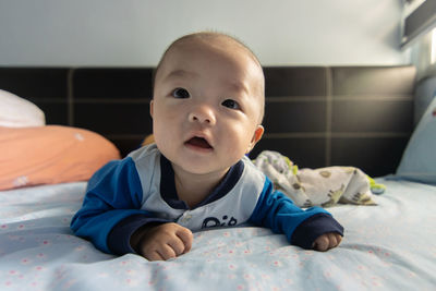 Portrait of cute baby lying on bed at home