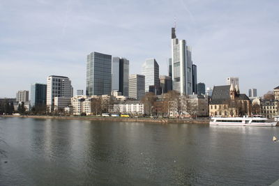 Sea by buildings against sky in city