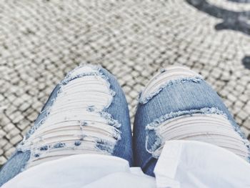 Midsection of woman wearing torn jeans while sitting outdoors