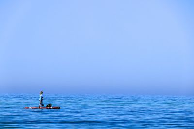 Full length of woman paddleboarding in sea against sky