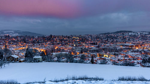 Illuminated city against sky during winter