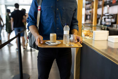 Businessman with refreshing drinks on tray in cafe