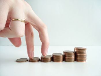 Close-up of hand holding coins over white background