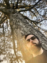 Low angle view of young woman on tree trunk