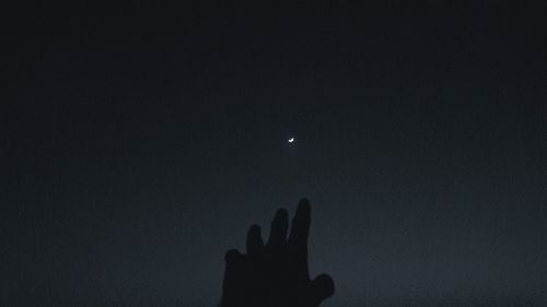 Low angle view of silhouette hand against clear sky at night