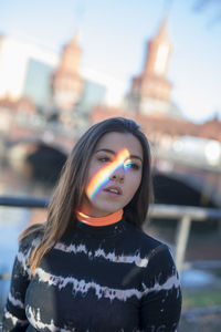 Young woman standing with prism light falling on face