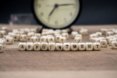 Close-up of appointment text made with toy blocks against alarm clock on wooden table