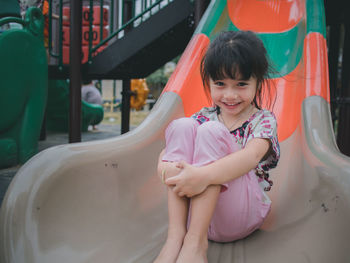 Portrait of cute smiling girl sliding in playground