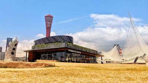 Buildings in field against sky