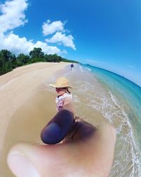Man wearing sunglasses on beach against sky