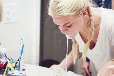 Close-up of young woman spitting while brushing teeth in bathroom