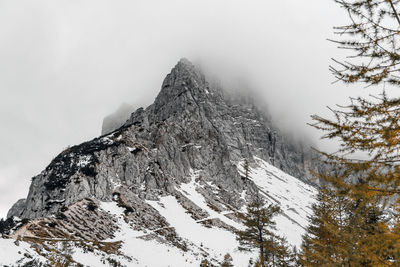 Scenic view of snowy slopes under misty rocky mountain in julian alps in slovenia