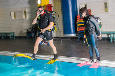 Full length of man and woman scuba diving in swimming pool