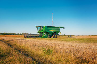 A green harvester on a field in the light of the evening sun