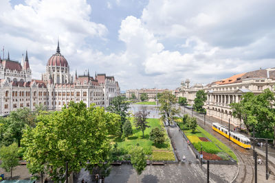 Hungarian parliament building and yellow vintage tram passing by in budapest, hungary - aerial view.