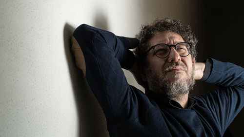 Mid-aged bearded man wearing glasses having pain on the neck and stretching at home in quarantine