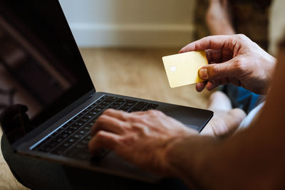 Crop man shopping online on floor