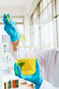 Midsection of scientist examining chemical in laboratory