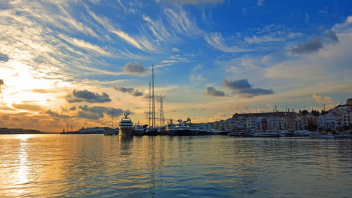 Sailboats moored on sea against sky during sunset