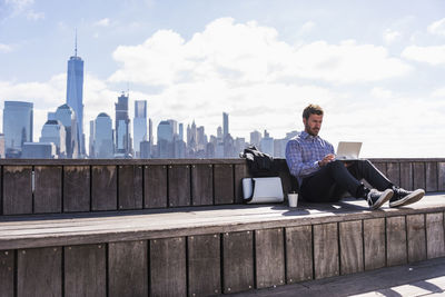 Usa, man using tablet at new jersey waterfront with view to manhattan