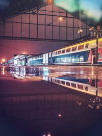 Train on illuminated street in city at night