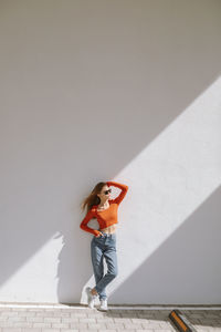 Minimalistic portrait of young girl with flowing hair near  wall on sunny day.  generation z trends.