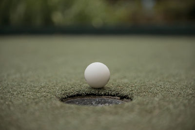 Close-up of golf ball by hole on court