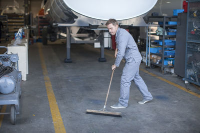 Industrial worker sweeping floor