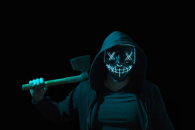 Portrait of man wearing mask against black background