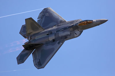 Low angle view of airplane flying against clear blue sky