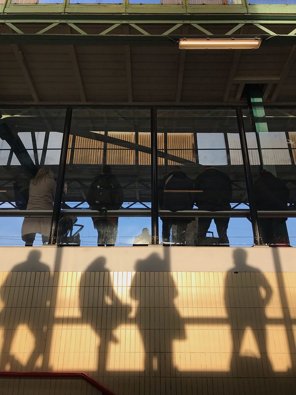 LOW ANGLE VIEW OF PEOPLE ON GLASS BUILDING