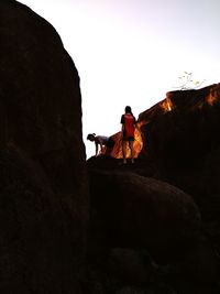 Two girls climbing on rock against clear sky